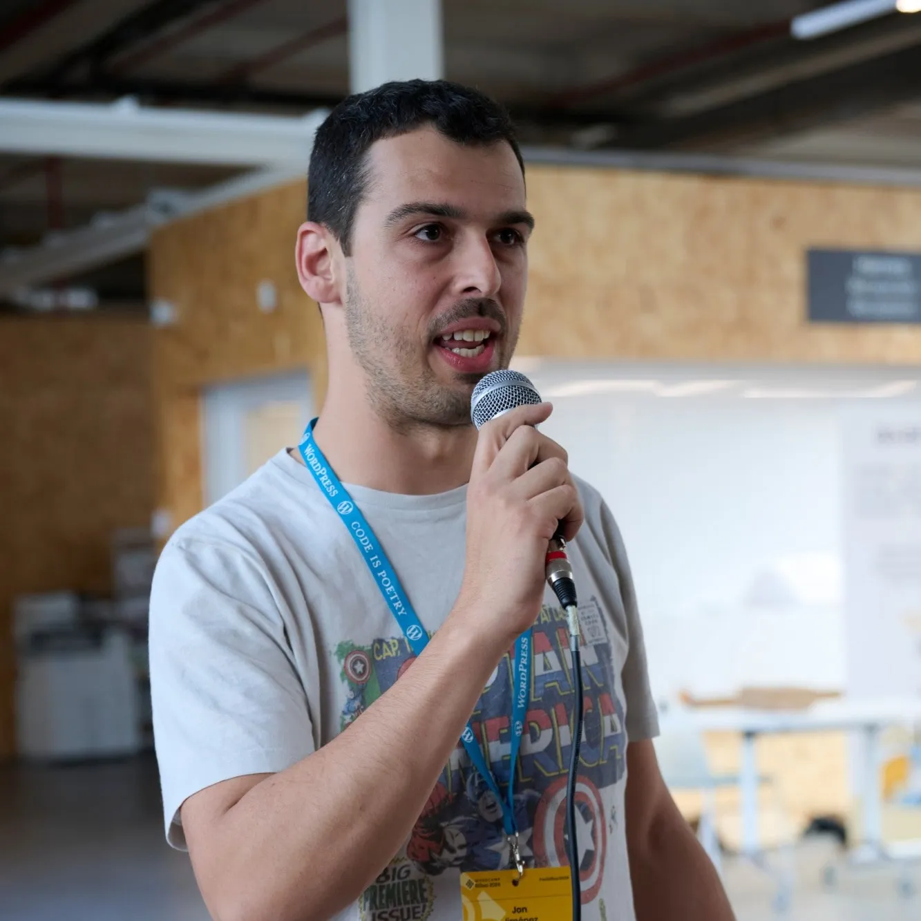 Jon Jiménez hablando con un micrófono en la mano, con la acreditación de la WordCamp Bilbao 2024